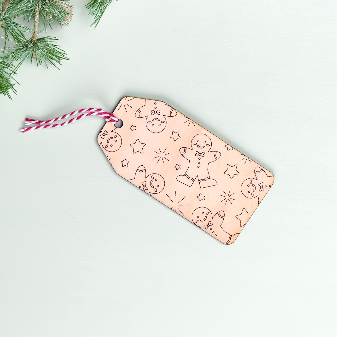 A wooden gift or stocking tag with an engraved pattern of gingerbread men