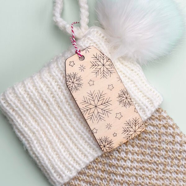 A wooden gift or stocking tag with an engraved pattern of snowflakes