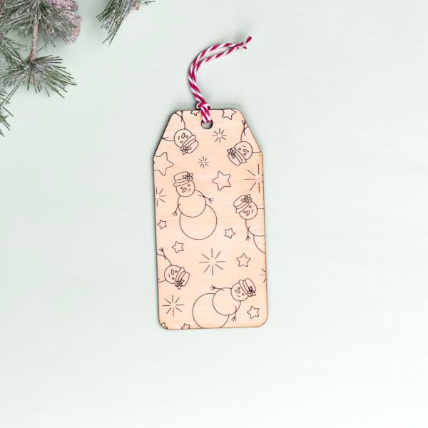 A wooden gift or stocking tag with an engraved pattern of snowmen